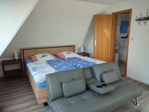a bedroom with a bed and a couch with a chair at Pension Feuerschiff in Borkum