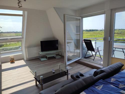a living room with a couch and a tv and windows at Pension Feuerschiff in Borkum