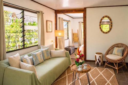 a living room with a green couch and a table at Matira Sunset House N659 DTO-MT in Bora Bora