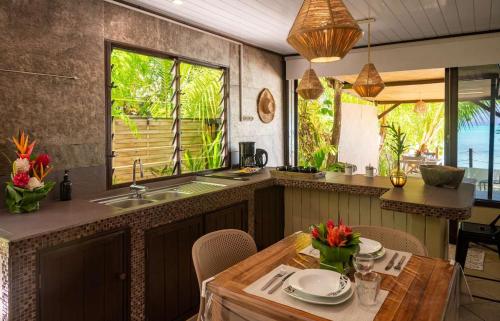 a kitchen with a sink and a table with chairs at Matira Sunset House N659 DTO-MT in Bora Bora