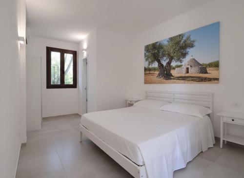 a white bedroom with a bed and a painting on the wall at Agriturismo Tenuta La Siesta in Gallipoli