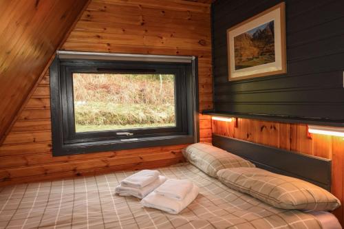 a room with a window and two towels on a bed at 1 Bedroom Cabin with Mountain & Loch Views - Quiet Location between Glencoe & Ben Nevis in Onich