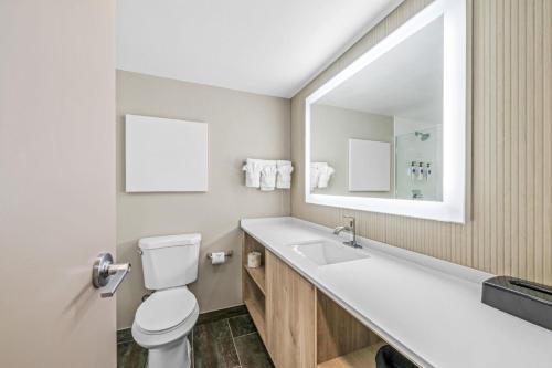 a bathroom with a toilet and a sink and a mirror at Sonesta Select Hotels Statesville in Statesville