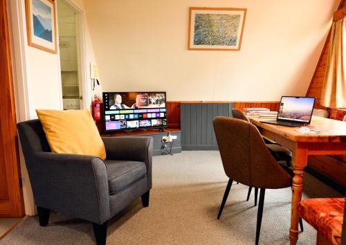 a living room with a chair and a table with a laptop at 1 Bedroom Cabin with Mountain & Loch Views - Quiet Location between Glencoe & Ben Nevis in Onich
