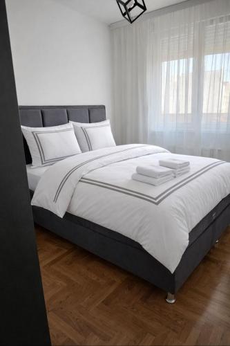 a white bedroom with a large bed with white pillows at Apartman NS PRIVATE PARKING in Novi Sad