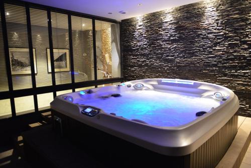 a bath tub in a room with a stone wall at L'Orchidée in Sévrier