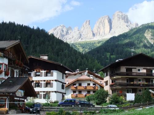 a group of buildings with mountains in the background at Central Dolomites Atelier - 3 Bedrooms in Campitello di Fassa