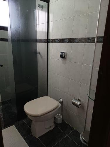 a bathroom with a toilet and a glass shower at Piemonte Flat Serra Negra in Serra Negra
