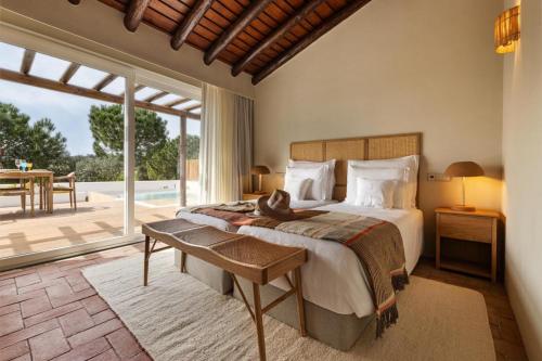 a bedroom with a bed and a large window at Herdade do Sobroso Wine Hotel & Villas - Small Luxury Hotels of the World in Pedrógão