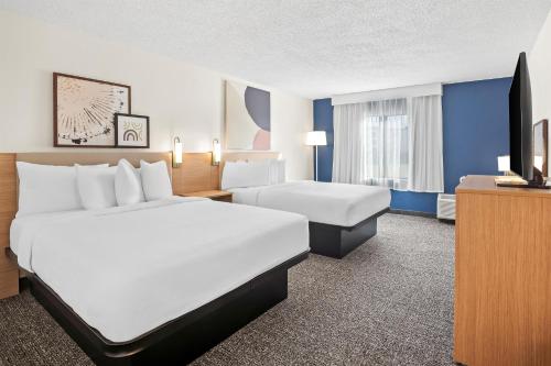 a hotel room with two beds and a television at Spark by Hilton Bettendorf Quad Cities in Bettendorf