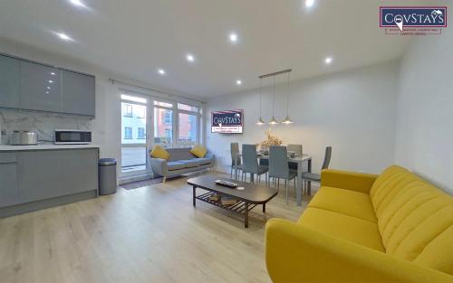 a living room with a yellow couch and a table at Beauchamp House - 2-bed apartment in Coventry City Centre, Free Parking, by COVSTAYS in Coventry