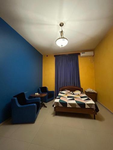 a bedroom with a bed and two blue chairs at Payl Hotel in Arrinj