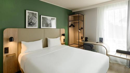 a bedroom with a white bed and a green wall at Campanile PRIME - Paris Bobigny in Bobigny