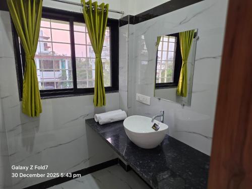 a bathroom with a sink and a mirror at Aanandi Resort in Shirdi