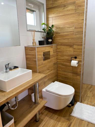 a bathroom with a white toilet and a sink at Domki pod Dębem in Wilkasy