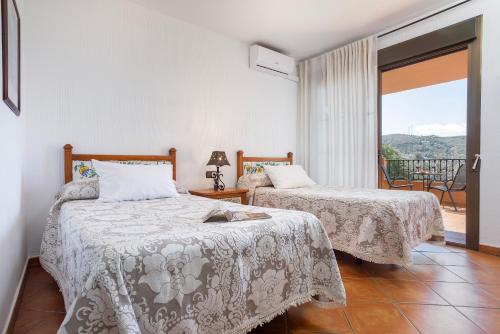 a bedroom with two beds and a balcony at Hotel Rural Sierra Tejeda in Alcaucín