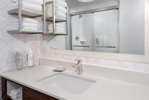 a white bathroom with a sink and a mirror at Hampton Inn & Suites Charlottesville at the University in Charlottesville