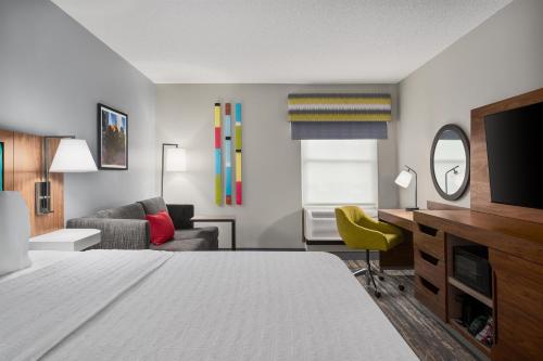 a hotel room with a bed and a tv and a couch at Hampton Inn & Suites Charlotte Arrowood Rd in Charlotte