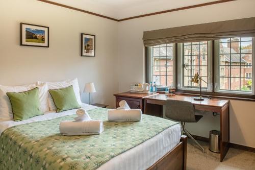 a bedroom with a bed with a desk and a desk at West Court- Jesus College in Cambridge