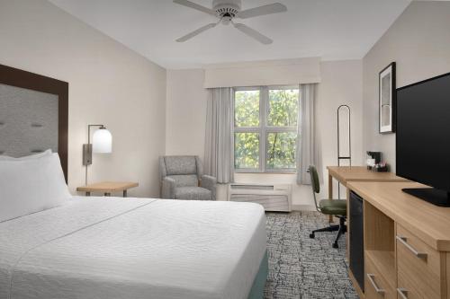 a hotel room with a bed and a desk and a television at Homewood Suites by Hilton Raleigh/Cary in Cary