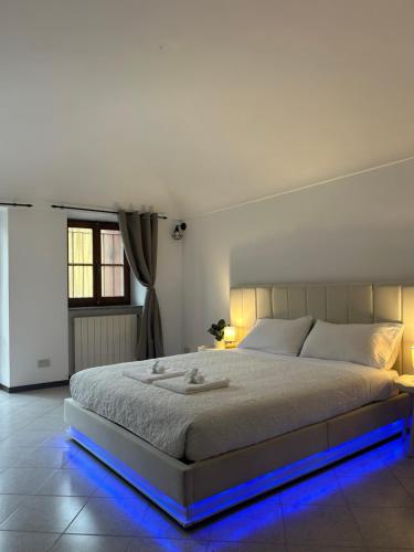 a white bedroom with a large bed with blue lights at Il Nido sul Lago B&B in Viverone