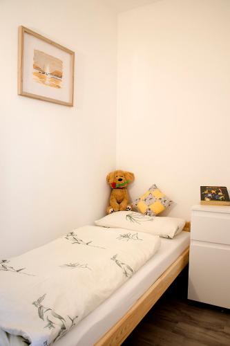 a teddy bear sitting on a bed in a bedroom at Am Blumenladen in Lübben