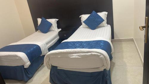 two beds with blue pillows in a room at شقق مساكن الراية المخدومه in Al Khobar