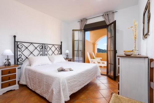 a bedroom with a white bed and a balcony at Apartamentos Sierra Tejeda in Alcaucín