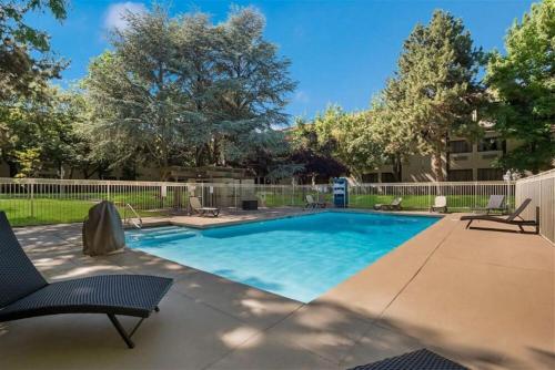 a swimming pool in a yard with chairs and a fence at SureStay Plus Hotel by Best Western Reno Airport in Reno