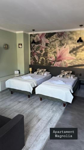two beds in a room with a painting on the wall at Apartamenty Jaskinia Solna in Ruda Śląska