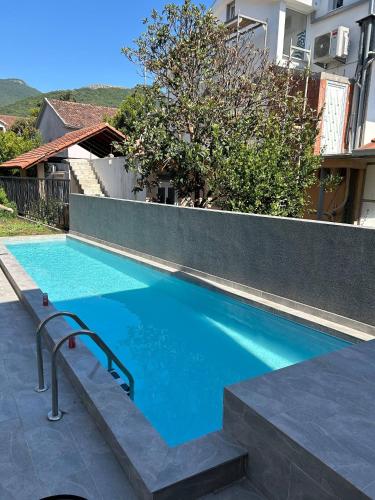 a blue swimming pool with a stair next to a building at Bohemian Beach Retreat in Donja Lastva