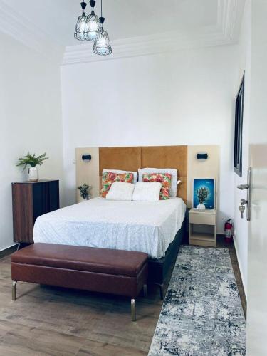 a bedroom with a large bed with a wooden headboard at Zac Mbao appartement meuble in Mbaw