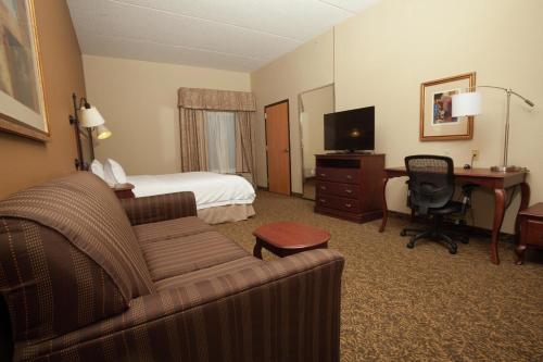 a hotel room with a couch and a bed and a desk at Hampton Inn Oneonta in Oneonta