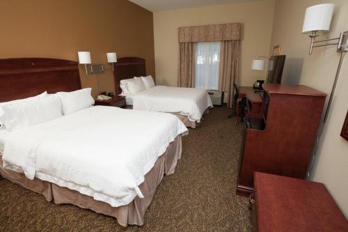 a hotel room with two beds and a desk at Hampton Inn Oneonta in Oneonta