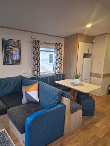a living room with a blue couch and a table at Buckingham Breeze Haven Caravan Hire Marton Mere Blackpool in Marton