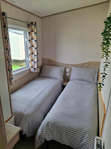 two beds in a small room with a window at Buckingham Breeze Haven Caravan Hire Marton Mere Blackpool in Marton