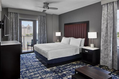 a hotel room with a bed and a balcony at Homewood Suites Savannah Historic District/Riverfront in Savannah