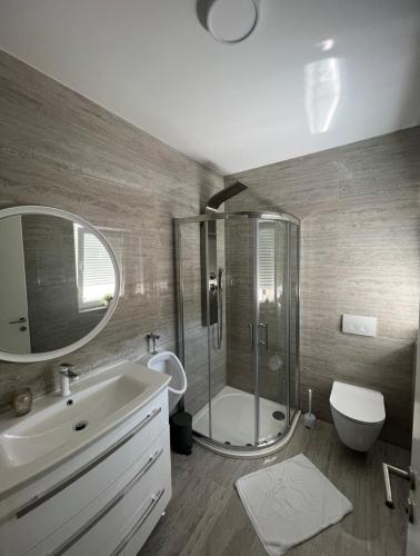 a bathroom with a sink and a shower and a toilet at Apartman Karmen in Brodarica