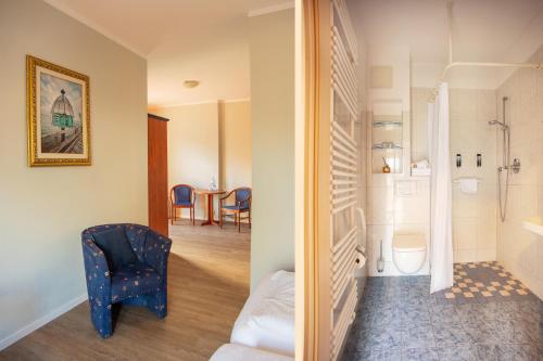a room with a bathroom with a shower and a chair at Hotel Ostseeblick - direkt hinter den Dünen in Karlshagen