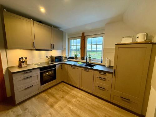 a kitchen with white cabinets and a wooden floor at FeWo Eich im Emsland in Langen