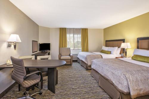 a hotel room with two beds and a desk at Candlewood Suites Indianapolis Northeast by IHG in Castleton
