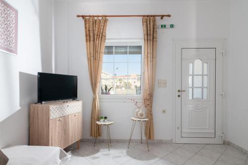 a living room with a tv and a window at GARDEN HOUSE, Kalamaki in Tympáki