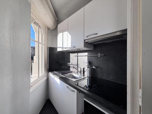a kitchen with white cabinets and a sink and a window at Nuit Panoramique - Studio - Wifi - 2 pers in Châtel-Guyon