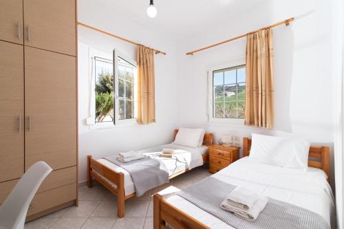 a bedroom with two beds and two windows at GARDEN HOUSE, Kalamaki in Tympáki