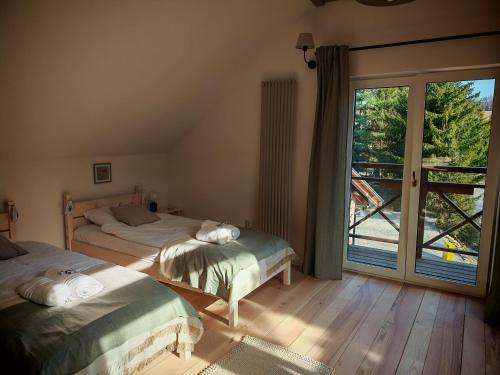 a bedroom with two beds and a large window at Słonna Chatka in Wujskie