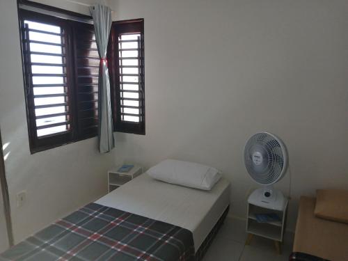 a bedroom with a bed and a fan and windows at Casa praia de Barra nova 6 km de Maceió in Marechal Deodoro