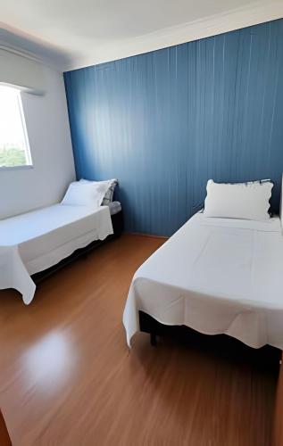 two beds in a room with a blue wall at Paz e natureza! Descanso e tranquilidade! in Rio das Ostras