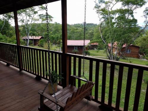 a swing on a porch with a view of a house at The Log Cab-Inn in San Ignacio