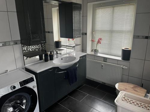 a bathroom with a sink and a washing machine at Hinterhaus-Idyll Markranstädt in Markranstädt