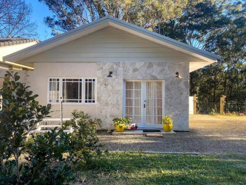 a small white house with a front door at Wisteria Hideaway in Coffs Harbour